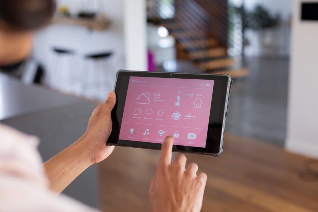 Hands of biracial man at home using tablet with smart home interface on screen